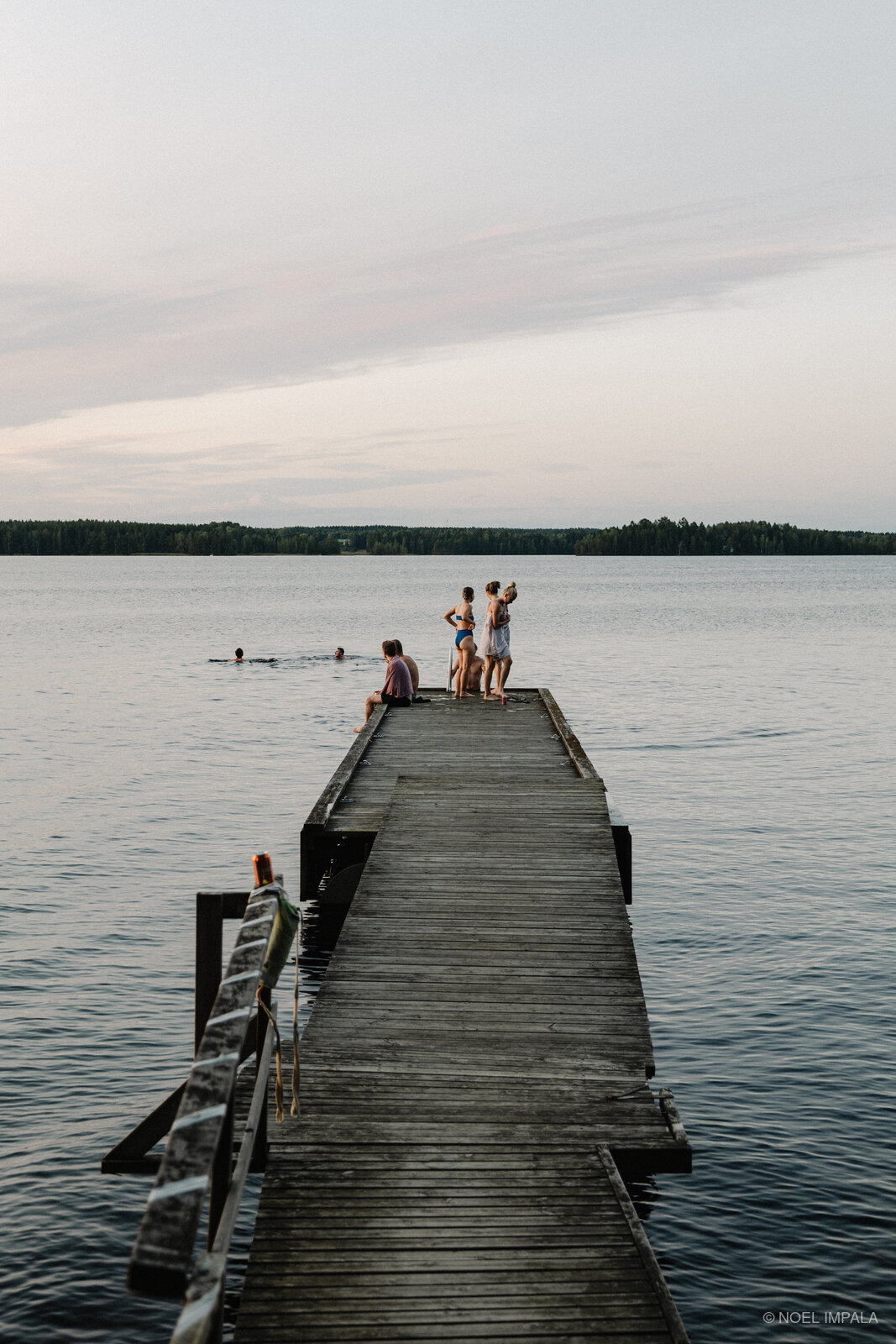 Friends standing on wooden dock over lake