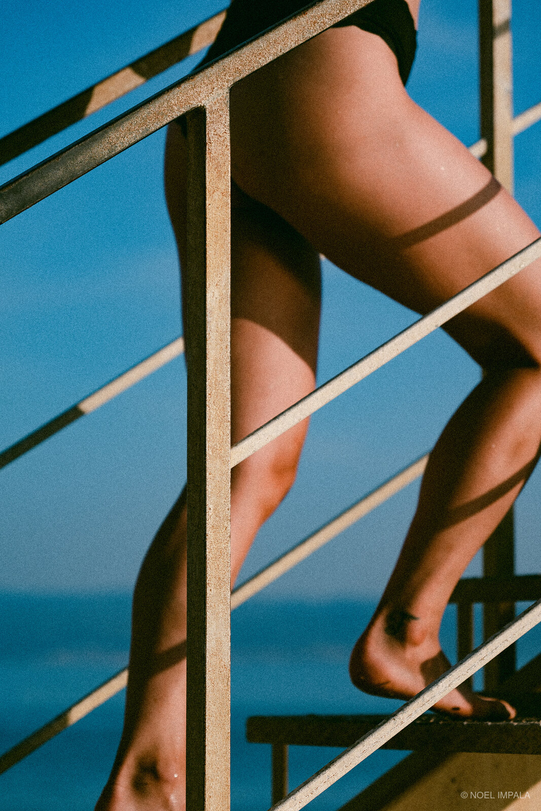 Legs on metal stairs blue sky
